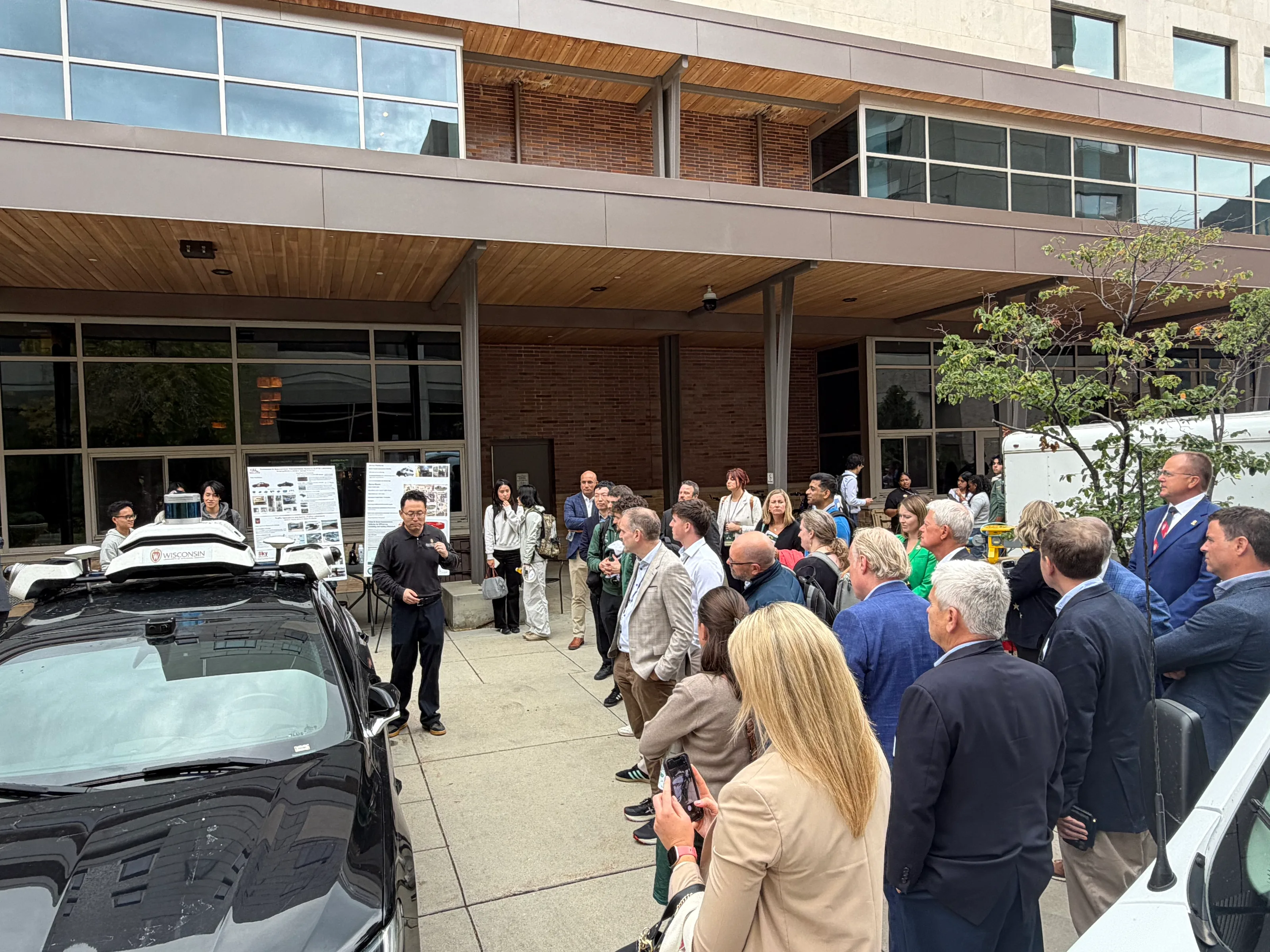 Researchers presenting connected and autonomous transportation projects beside the research fleet