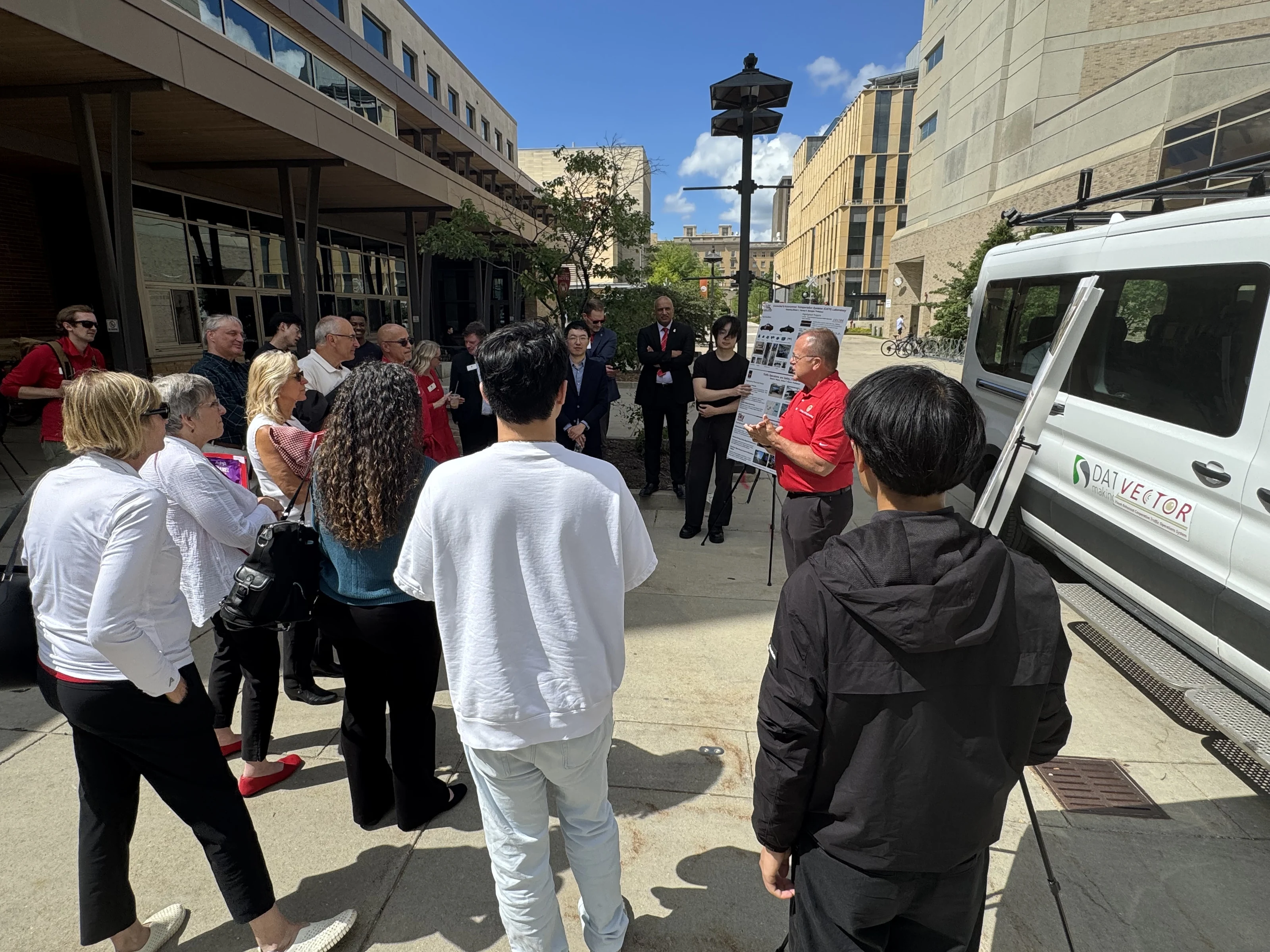 Guests gathered beside the autonomous shuttle at Union South
