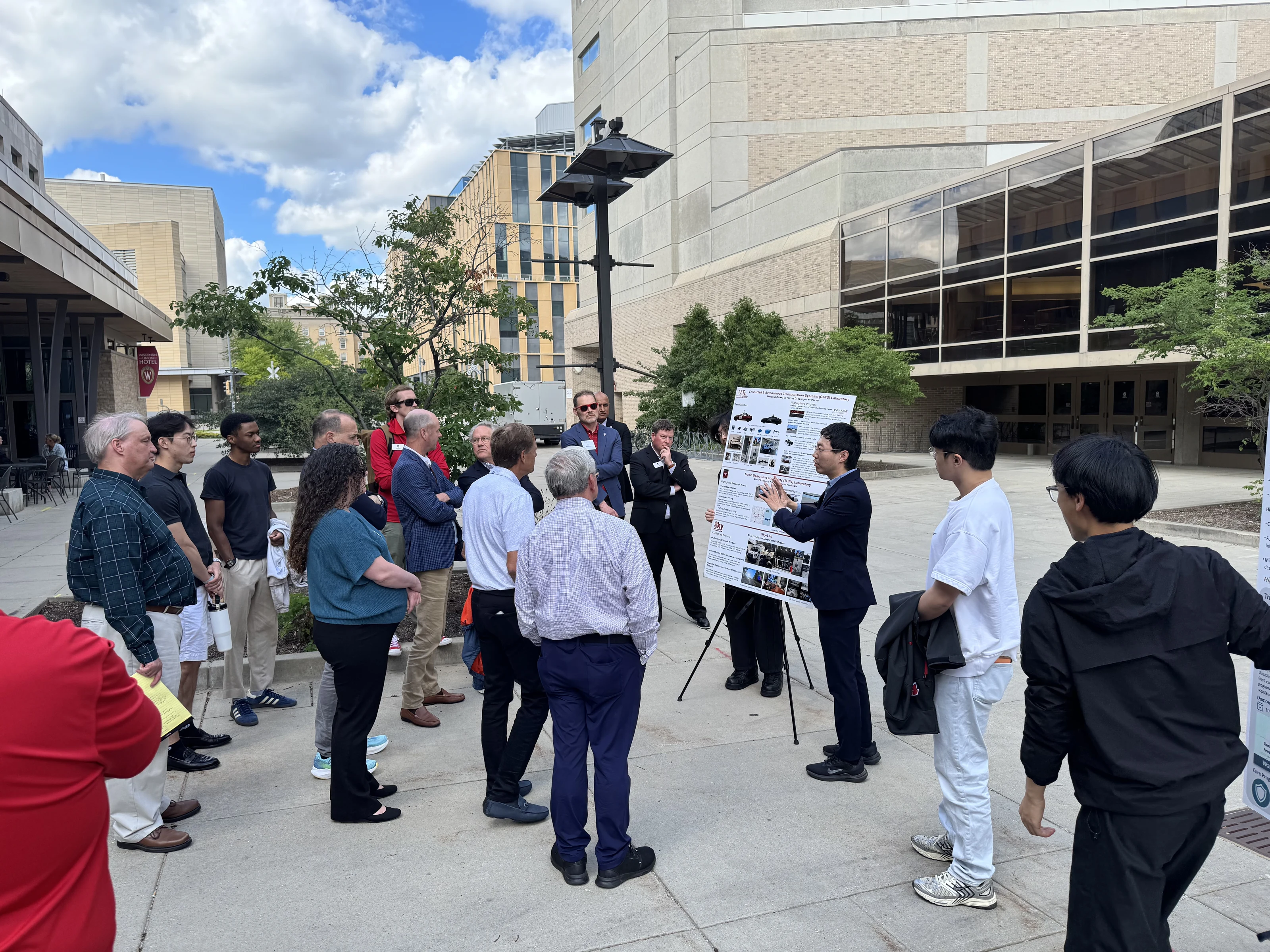 A graduate researcher presenting an autonomous vehicle research poster to WFAA guests